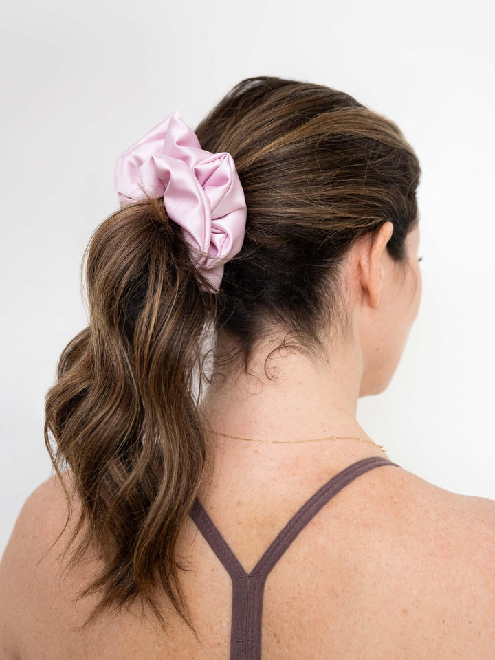 Side profile of a ponytail styled with a pink satin scrunchie