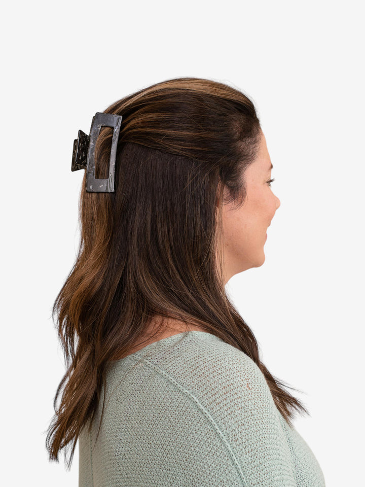 Model using Next Level claw clip in black onyx to hold a half-up hairstyle.