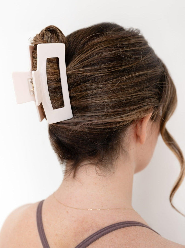 Side profile of model with brown hair wearing our Pale Pink claw clip in next level.