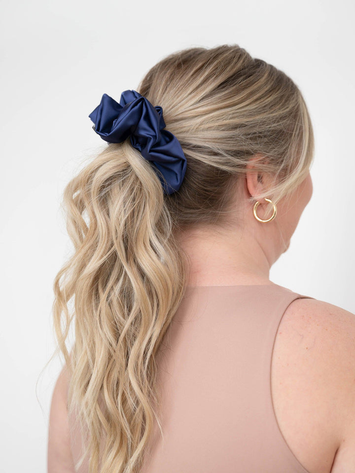 Back view of a woman with a ponytail wrapped in a navy satin scrunchie