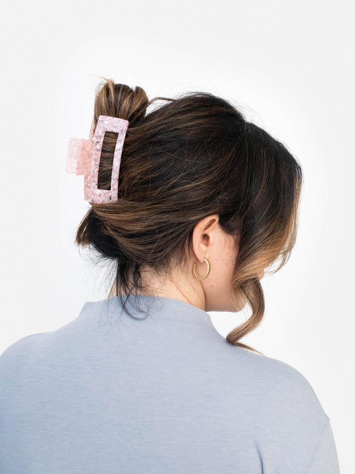 Side view of model wearing Next Level claw clip in rose quartz, securing a french twist hairstyle.