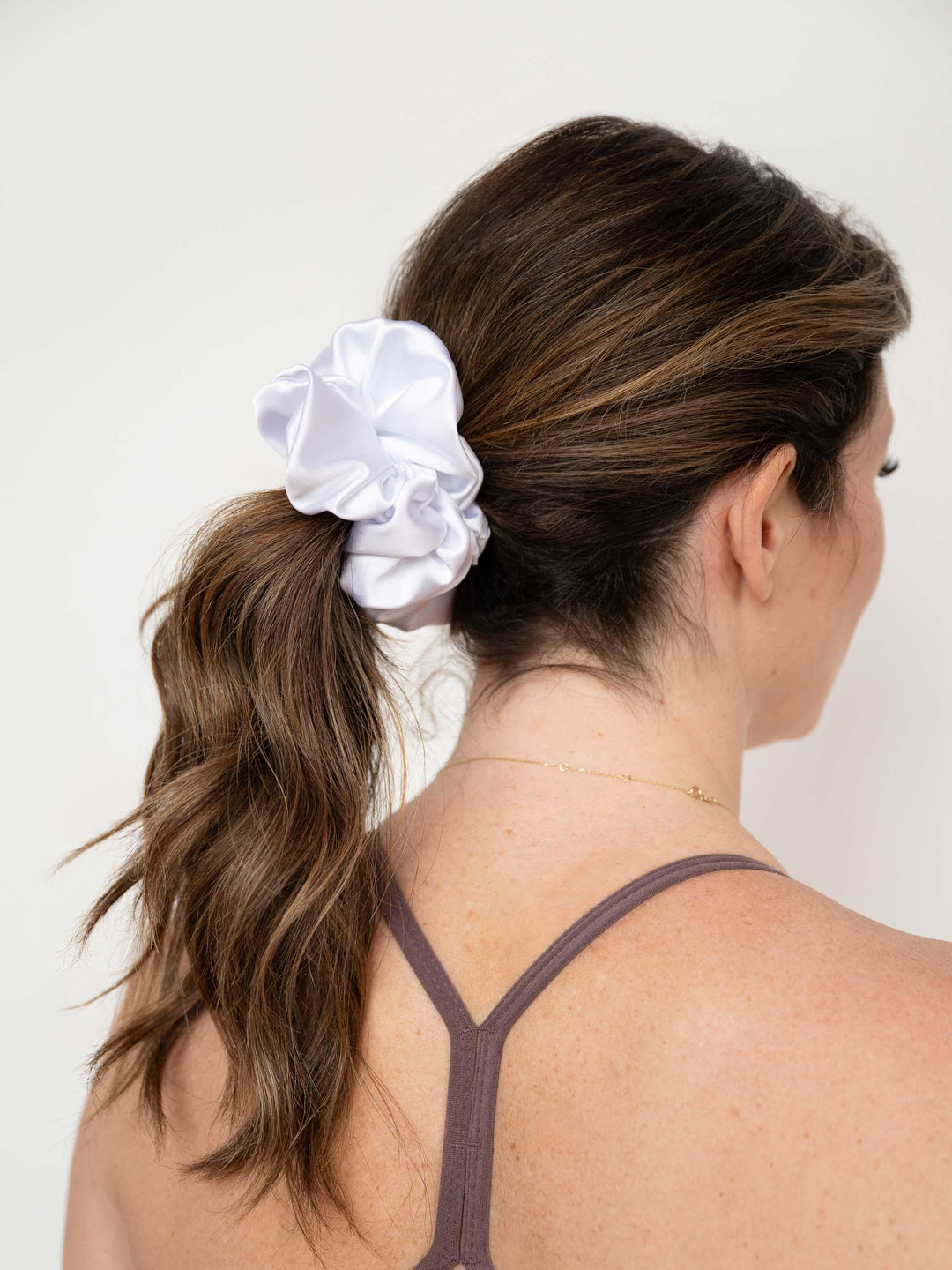 Woman wearing a bright white satin scrunchie - perfect for any bride-to-be